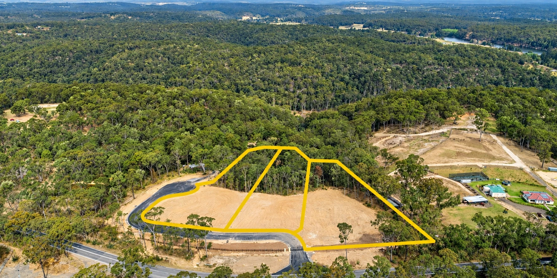 Aerial view of a FIDES subdivision site, with three lot boundaries marked in yellow among native bushland
